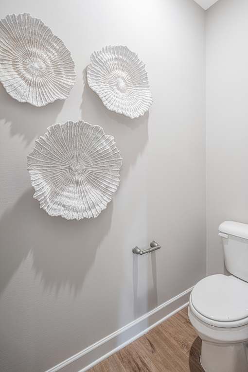 Three white plates are mounted on a wall above a toilet.