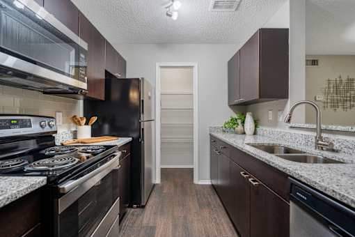 A kitchen with dark wood cabinets and a black stove top oven.