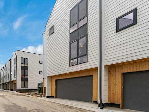 A row of modern houses with wooden sidings and dark grey garage doors.