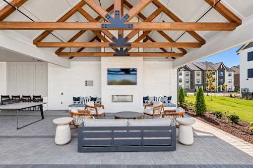 A patio with a grey couch and a wooden ceiling.