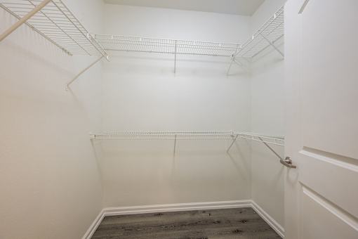 A white closet with a door and a grey floor.