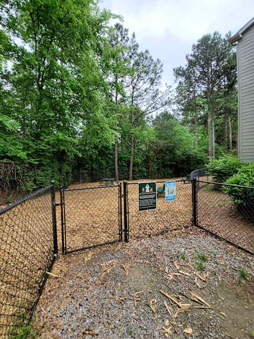 A fenced area with signs and trees in the background.