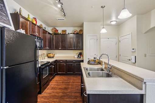 A kitchen with a black refrigerator and wooden cabinets.