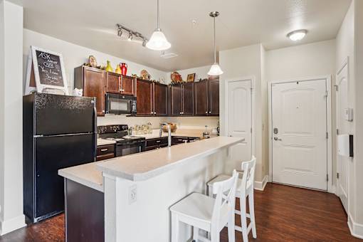 A kitchen with a black fridge and white cabinets.
