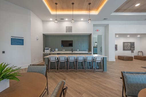 a communal area with a bar and chairs in a room with a table and chairs