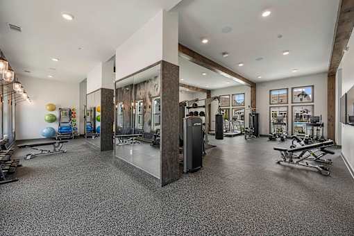 a gym with weights and cardio equipment in a building with windows