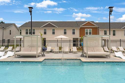 a swimming pool with chairs and umbrellas in front of a building