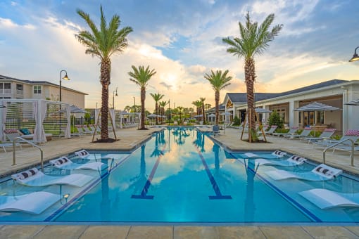 a resort style pool with lounge chairs and palm trees