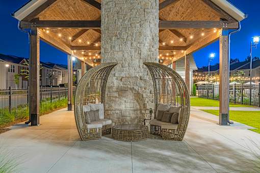 two rattan hanging chairs in front of a stone fireplace