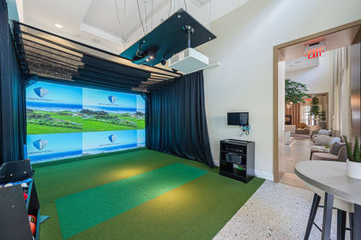 a game room with a golf simulator and a green carpet