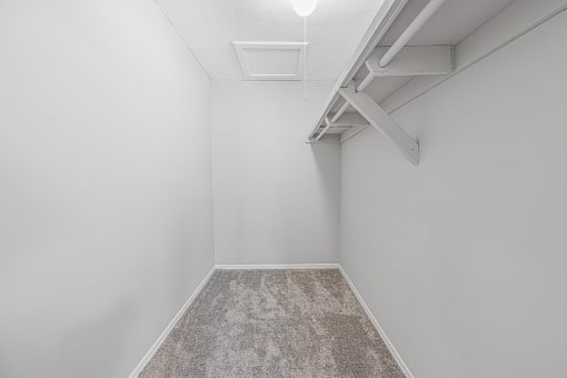 an empty room with white walls and a carpeted floor and a white ceiling fan