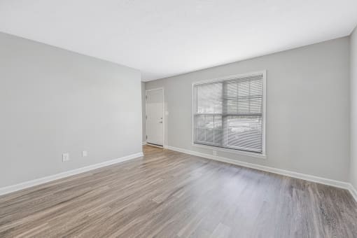 an empty living room with a large window and wood flooring