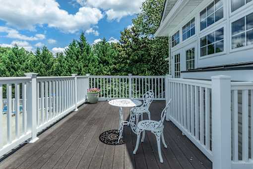 A white table and chairs are on a wooden deck.