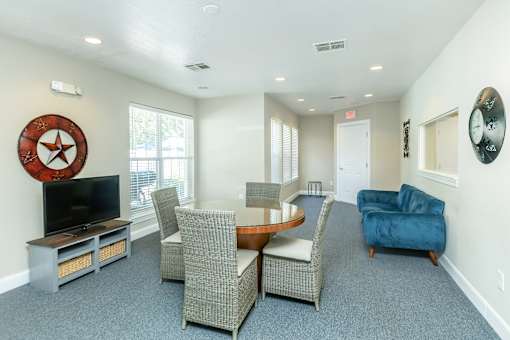 A living room with a TV, chairs, and a clock on the wall.