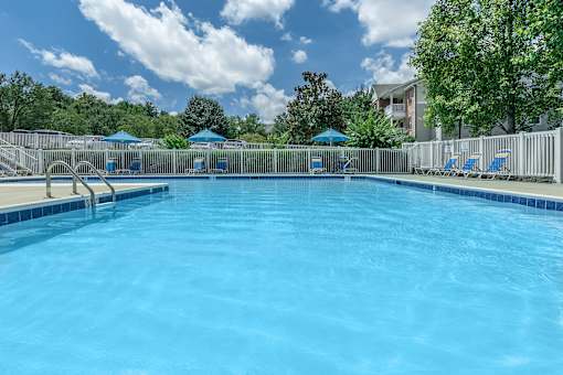 A large swimming pool with blue water and white lounge chairs.