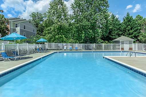 A large swimming pool surrounded by a fence and trees.