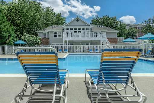Two blue and yellow chairs are in front of a pool.