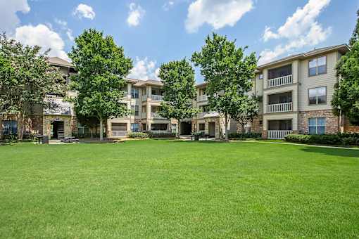 A grassy field in front of apartment buildings.
