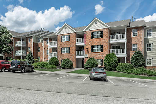 A large brick apartment building with a parking lot in front.