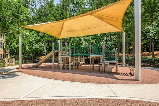 A playground with a yellow canopy and a slide.