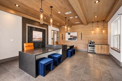 A modern kitchen with a wooden ceiling and a large island with blue stools.