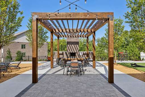 A wooden pergola with a table and chairs underneath it.