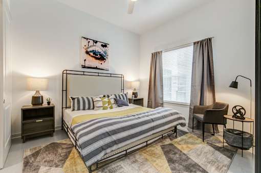 A bedroom with a bed, nightstands, and a chair.