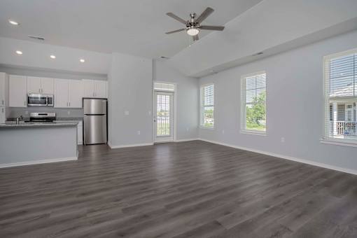 Two Bedroom Luxury Apartments In Jeffersonville, IN - The Laurel - Kitchen with Stainless-Steel Energy Efficient Appliances, Granite Countertops, White Cabinets, and View of Unfurnished Living Area with Ceiling Fan.