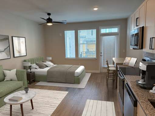 A well-lit bedroom with a green couch and a bed with a white headboard.