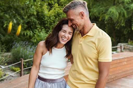 A man and a woman are standing close together on a wooden deck.
