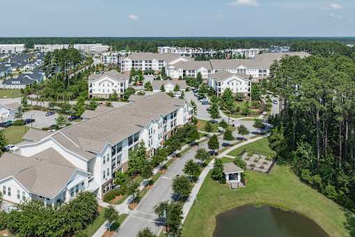 A bird's eye view of a residential area with houses, roads, and a pond.