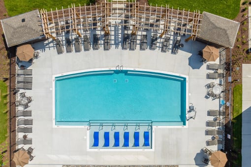 Apartments for Rent in Mt Juliet, TN - The Enclave at Providence - Aerial View of Resort-Style Pool with Sundeck, Submerged and Poolside Lounge Seats, Gazebos, and Umbrella Tables with Chairs.