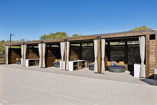 A wooden structure with white curtains and a round seating area in front.