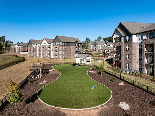 A large grassy area with a walking path in the middle of a housing complex.