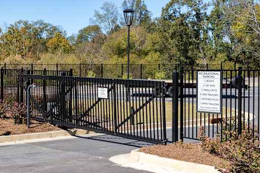 A black gate with a sign that says "Recreational Parking" and lists the types of vehicles allowed.