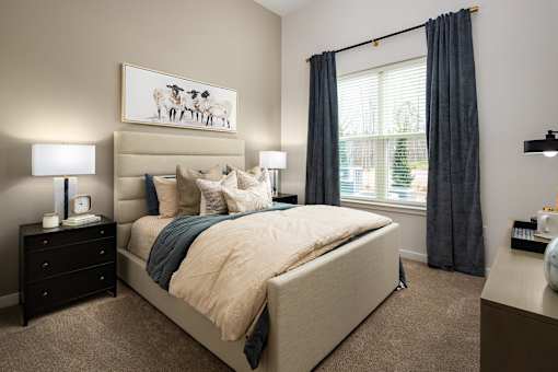 Pet-Friendly Luxury Apartments in Cumming, GA - Aura Creekside - A Modern Bedroom With Upholstered Bed, Neutral Bedding, And Matching Nightstands.