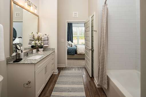 A bathroom with a white tile shower and a white sink.
