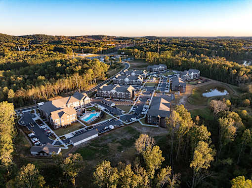 A bird's eye view of a resort with a swimming pool and surrounded by trees.