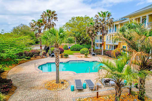A pool surrounded by palm trees and a house.