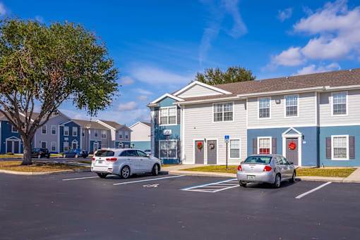A parking lot with cars and apartment buildings.