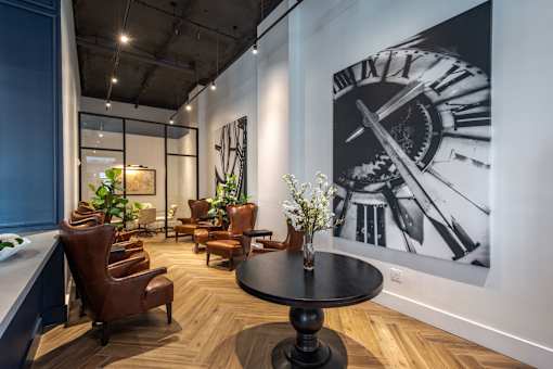 A large clock is on the wall behind a table.