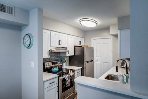 A kitchen with a white counter and a clock on the wall.