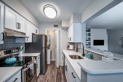 A kitchen with white cabinets and a black fridge.