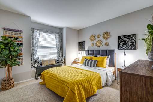 A bedroom with a yellow bedspread and a grey bed.