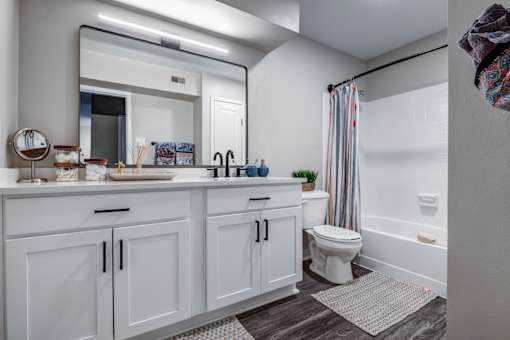A white bathroom with a toilet, sink, and mirror.
