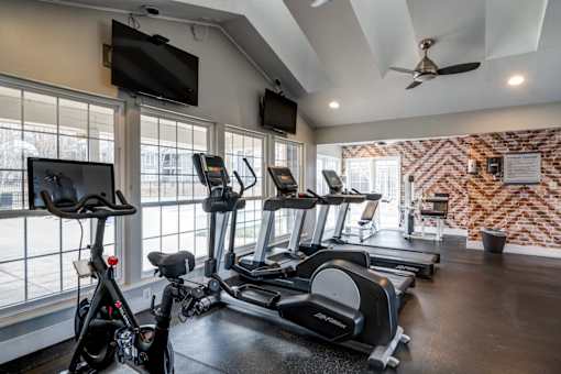 A gym with treadmills, exercise bikes, and a television.
