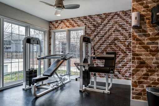 A gym room with a brick wall and a rowing machine.