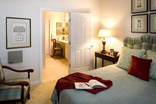 A bedroom with a bed, a chair, a desk, and pictures on the wall.