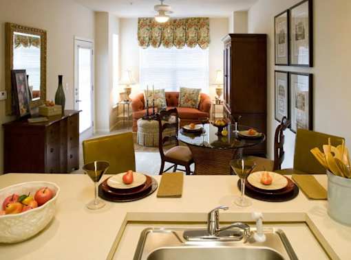 A kitchen with a table set for two with a bowl of fruit on it.