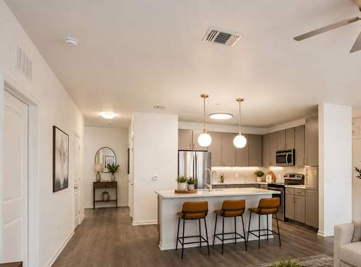 A modern kitchen with a bar area and a ceiling fan.